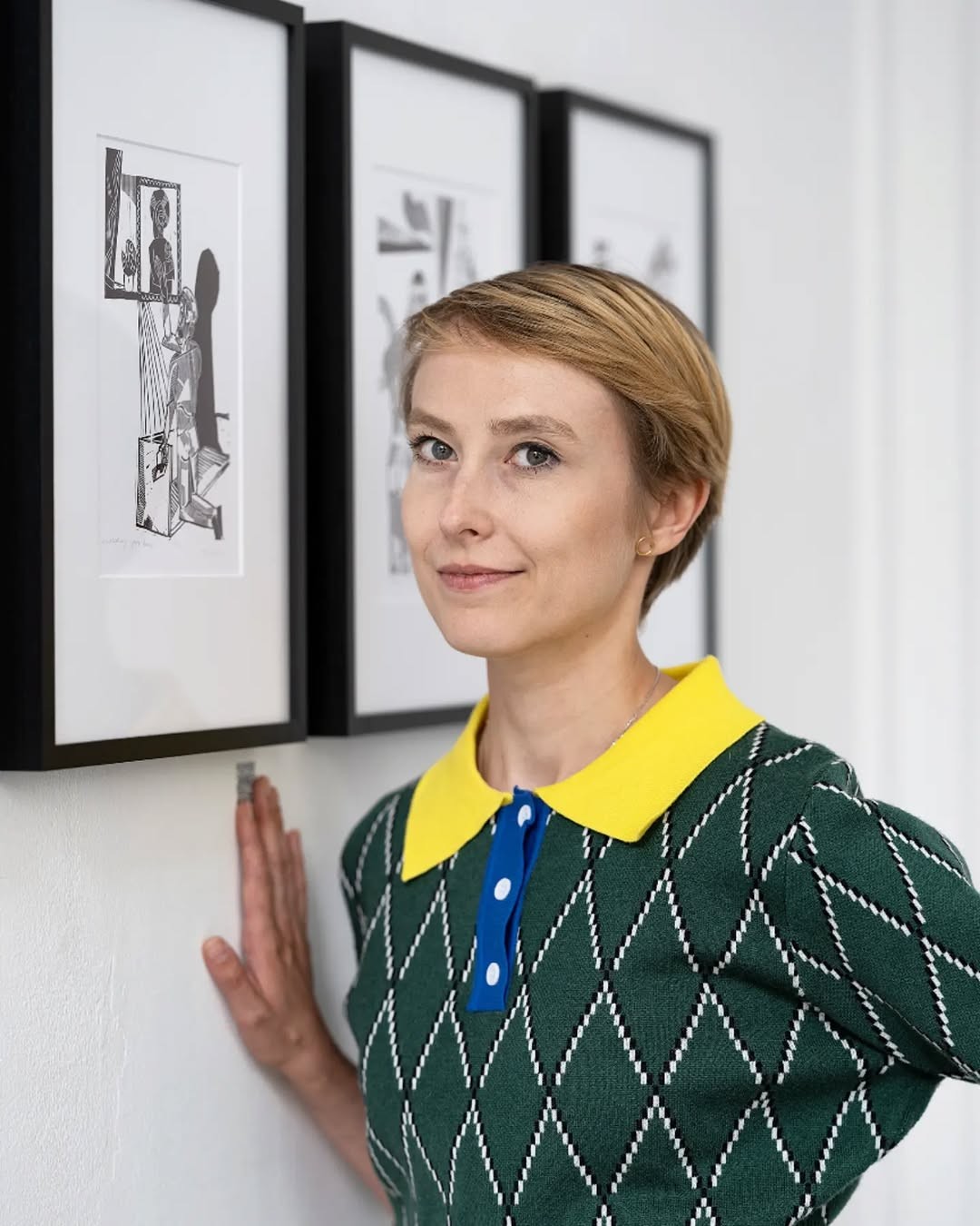 “200 Revelations” exhibition by Sylwia Zawiślak at Raster Gallery, Warsaw, 2022. Linocut prints depicting symbolic figures are displayed on the walls. Visitors are viewing the artworks.