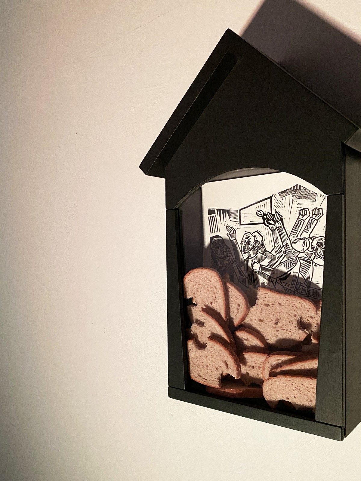 An art installation consisting of five black wooden shrines. Inside each shrine, there is a linocut depiction of Saint Apollonia’s martyrdom