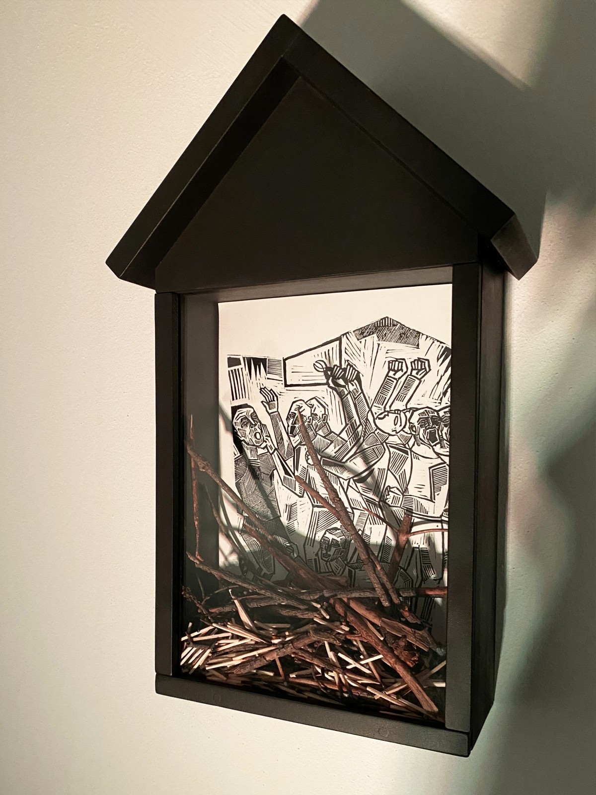 An art installation consisting of five black wooden shrines. Inside each shrine, there is a linocut depiction of Saint Apollonia’s martyrdom