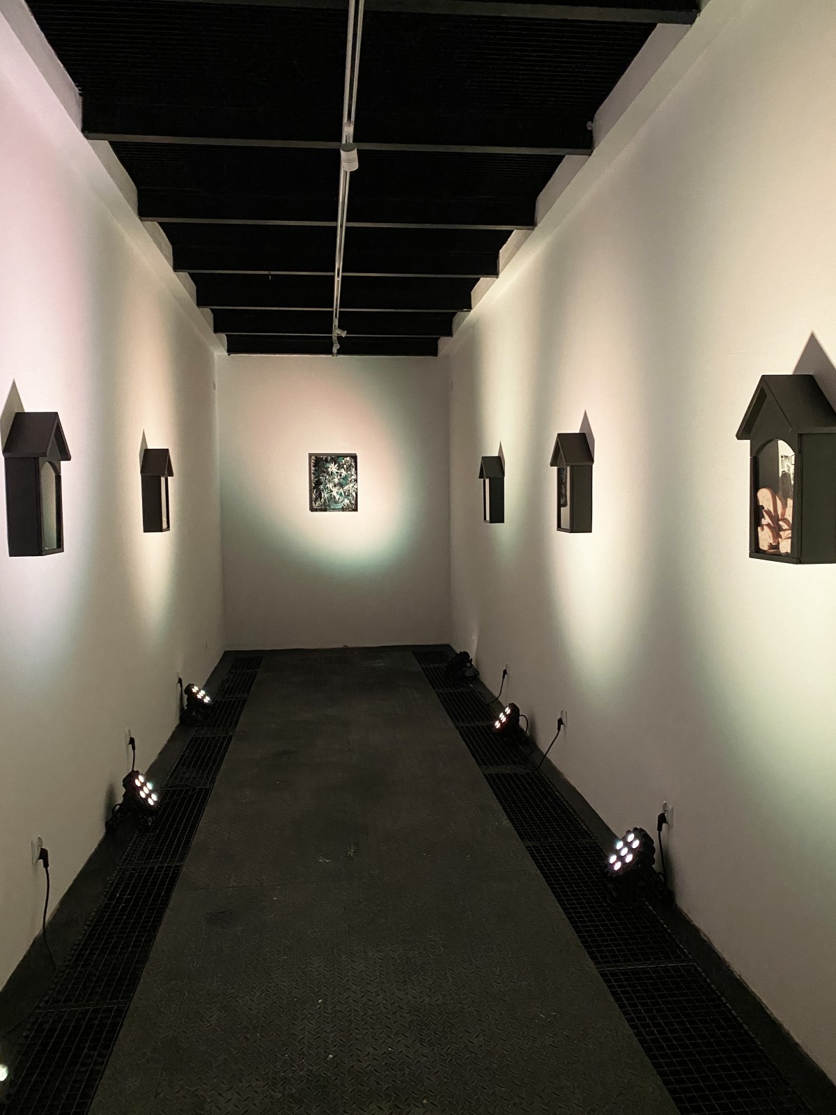 An art installation consisting of five black wooden shrines. Inside each shrine, there is a linocut depiction of Saint Apollonia’s martyrdom